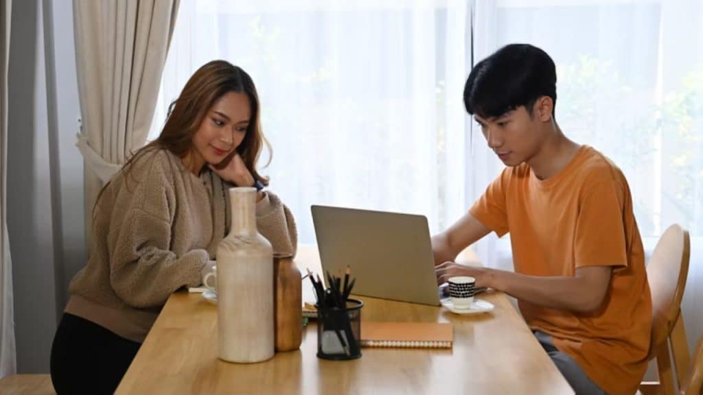 Man showing wife something on laptop while she looks disinterested