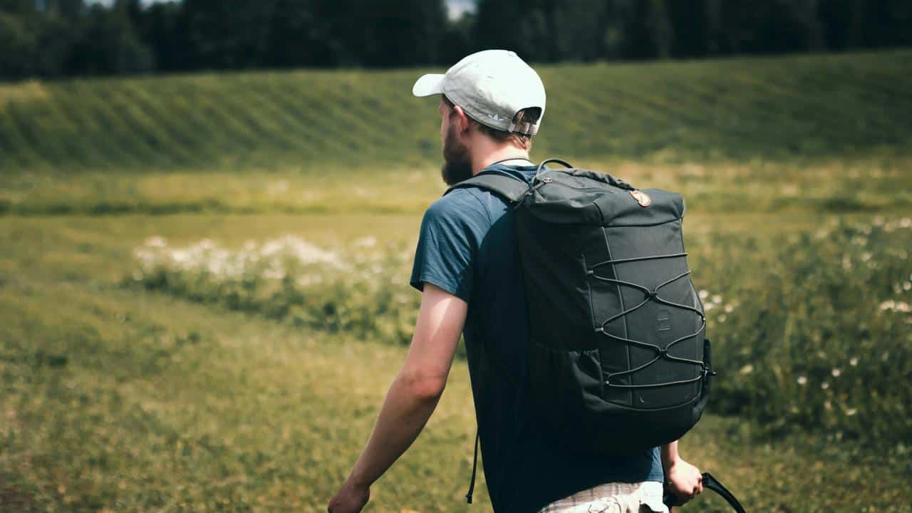 A man hiking with a backpack in a grassy field.