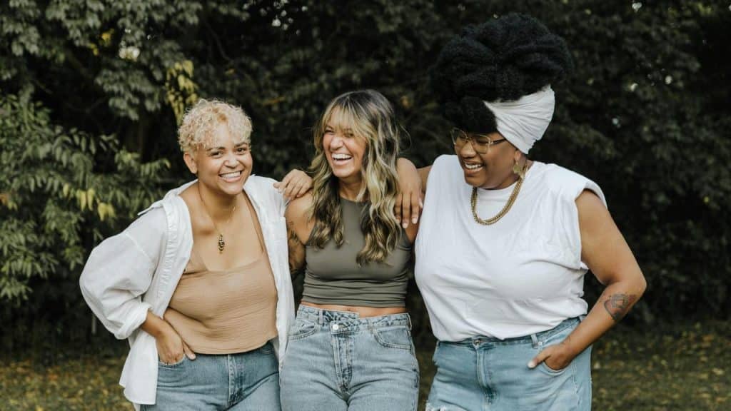 A group of three friends laughing together outdoors.