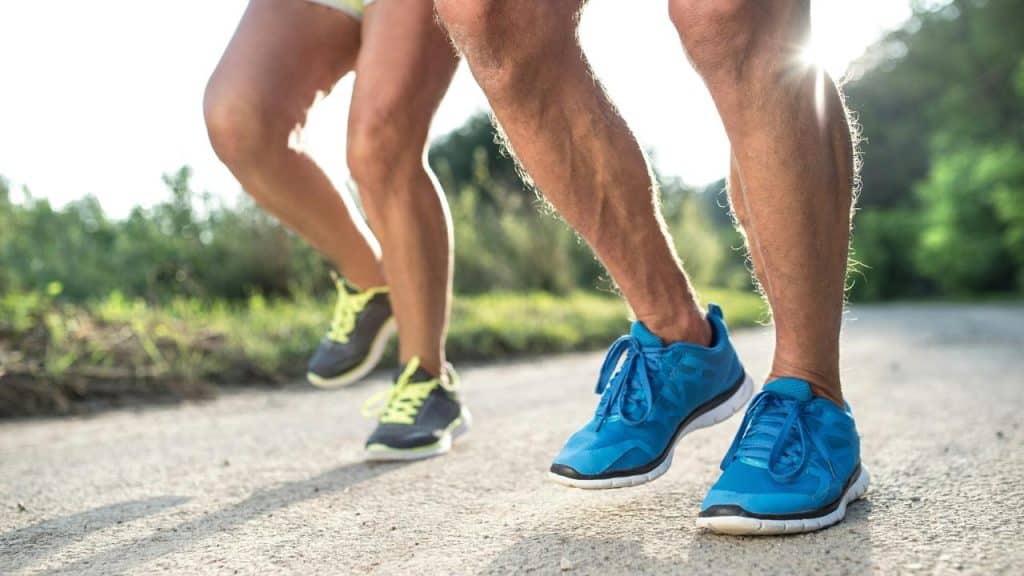 A pair of runners jogging on a sunlit trail.