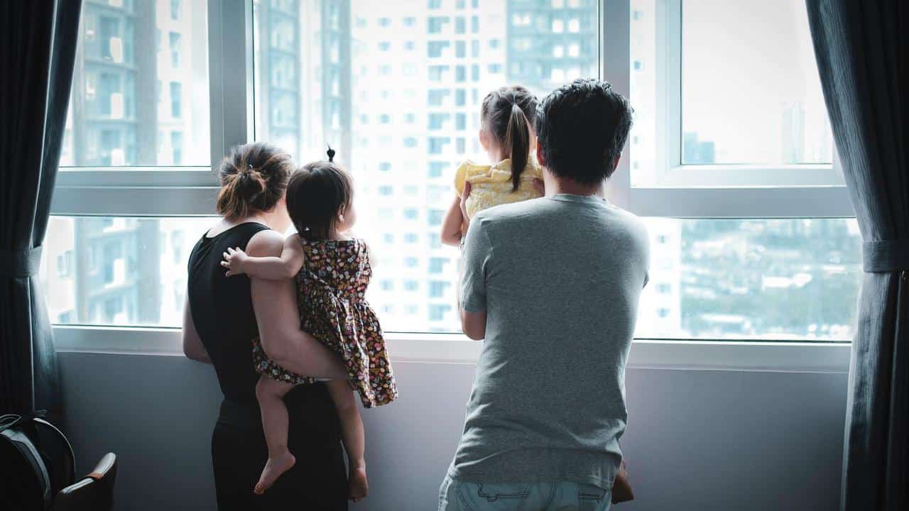 A family with two kids looking out a window.