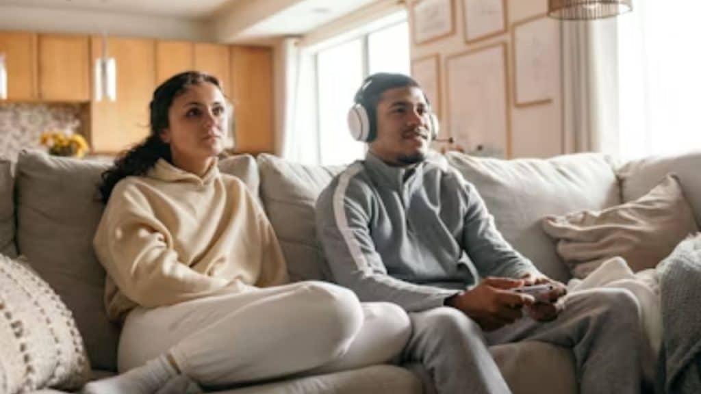 Husband and wife sitting on couch, both focused on separate screens