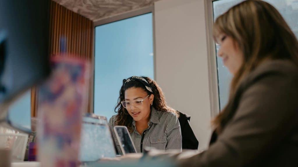 A woman speaking while looking at her phone in a meeting.