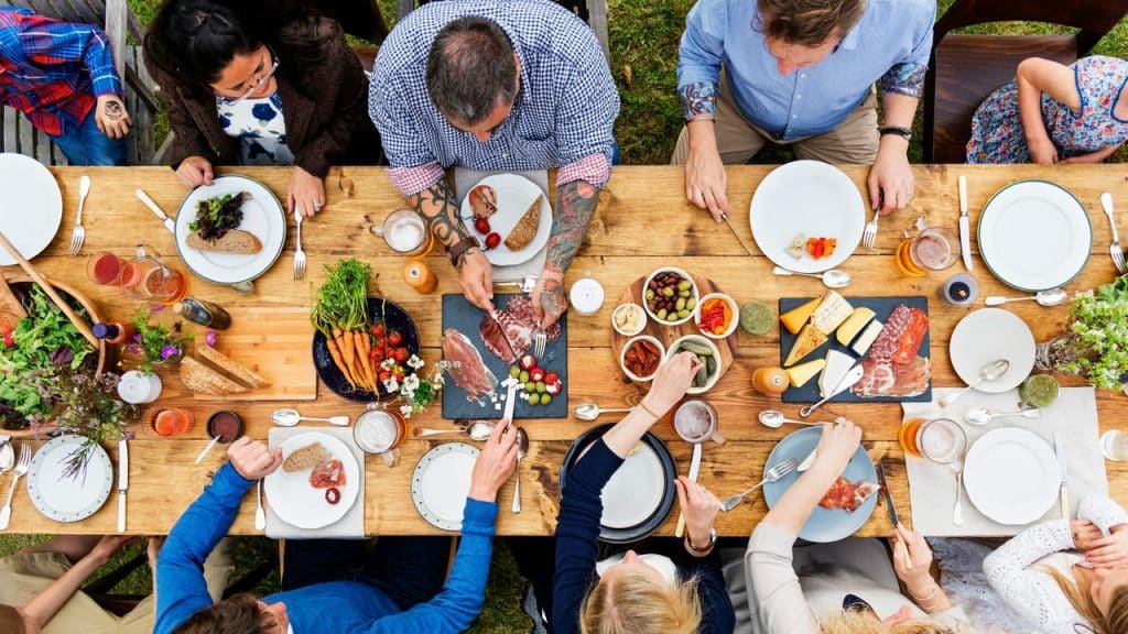 A group of people enjoying a shared meal at a large outdoor table.
