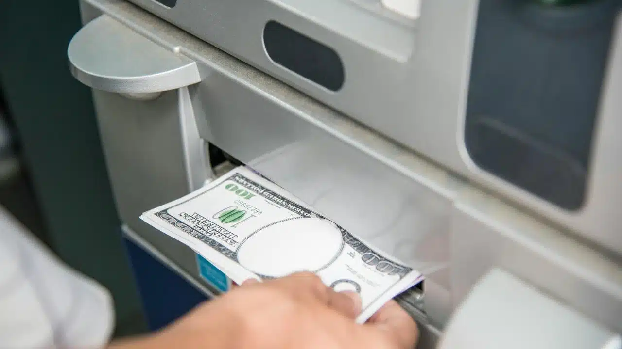 A hand withdrawing cash from an ATM.