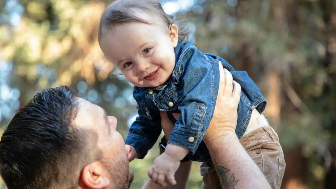 A father lifting his smiling baby in the air.