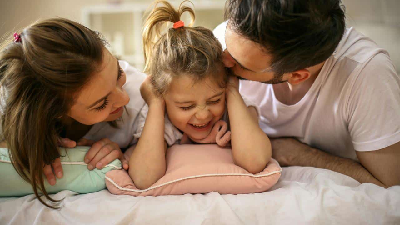 A happy family playing on a bed.