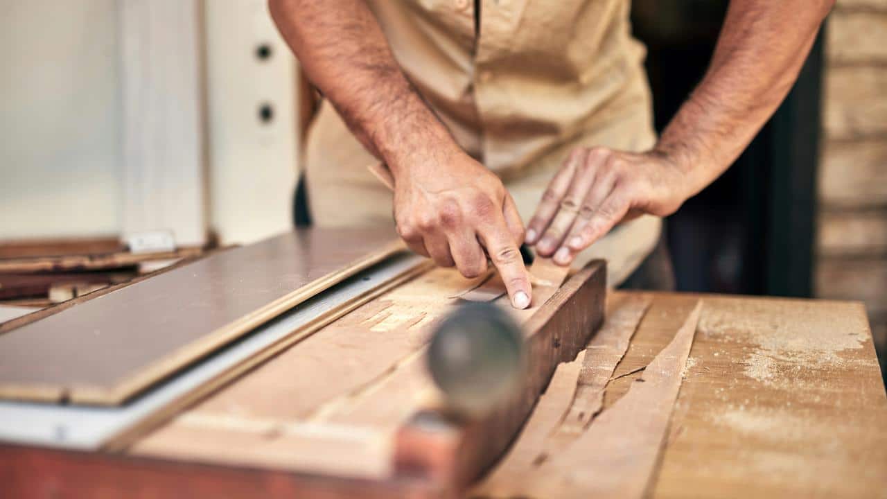 A man working with wood on a table saw.