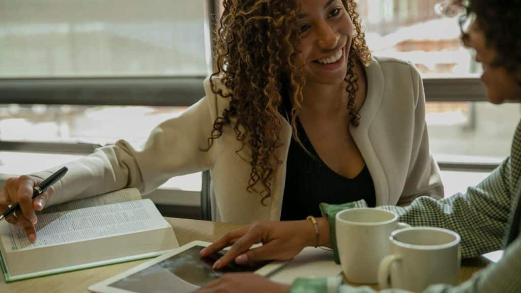 A woman smiling while talking with a colleague over coffee.