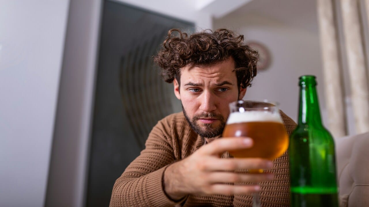 A man drinking at home by himself.