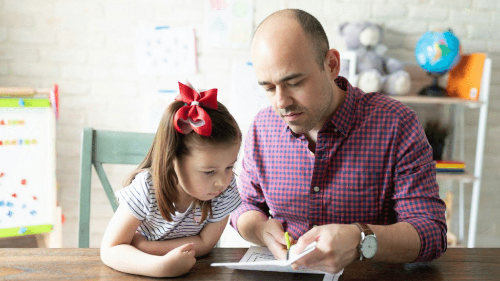 A man and a young girl sit at a table looking at a worksheet.
