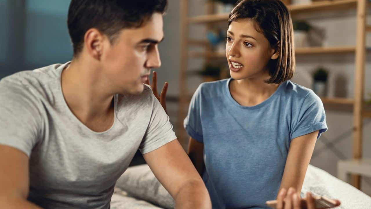 A woman talking seriously to a man while sitting together.