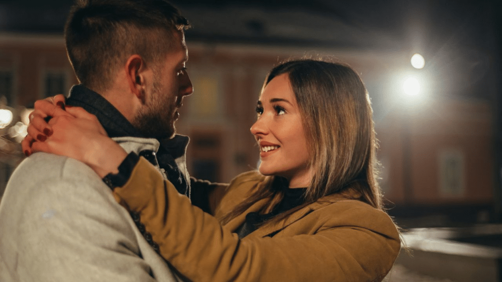 A couple is hugging and gazing into each other's eyes at night.