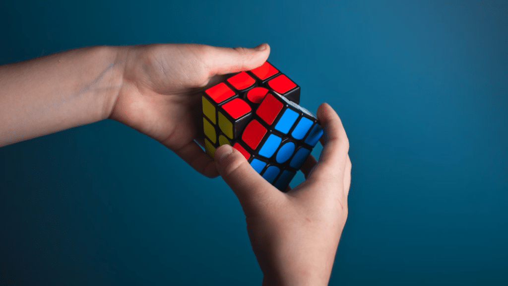 Hands manipulating a red, blue, and yellow Rubik's Cube.