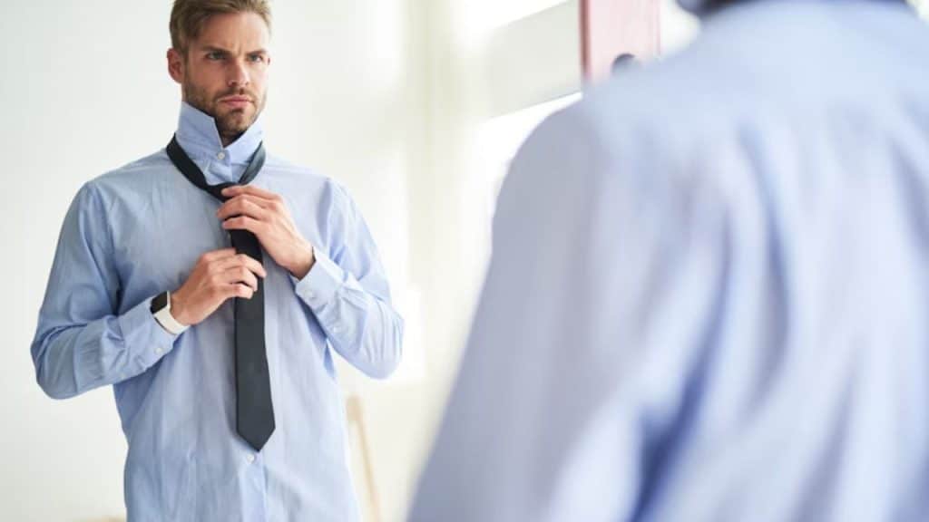 Man adjusting his tie in a mirror before work