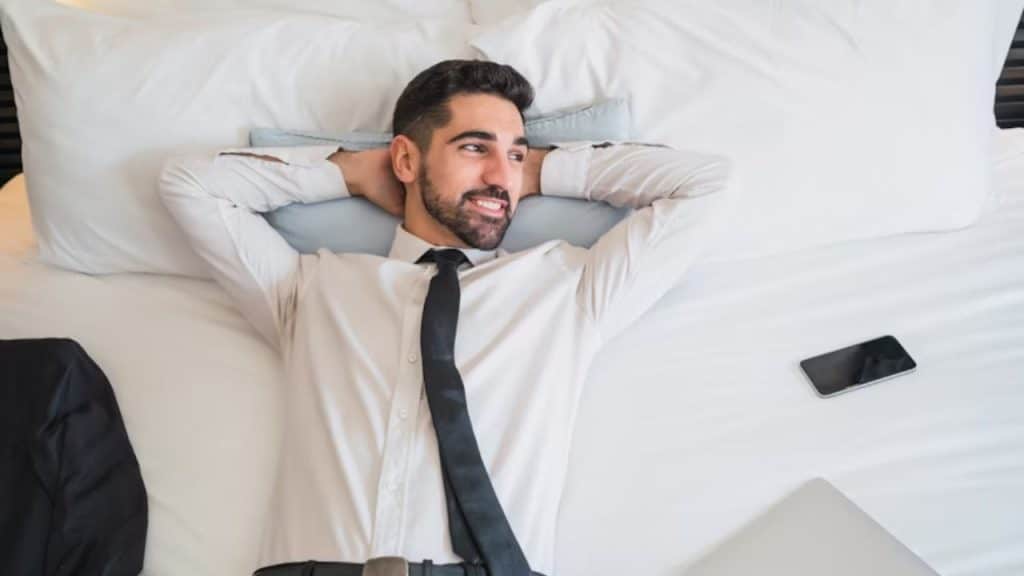 A man lying on a bed, looking contemplative with natural light coming in from the window