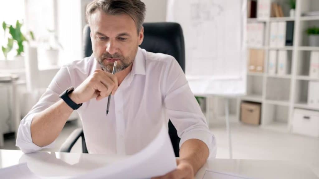 Man reviewing bills at a table with a stressed expression