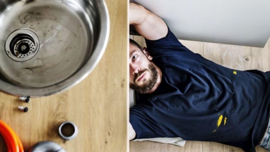 Man stressed while fixing a leaking sink under the counter