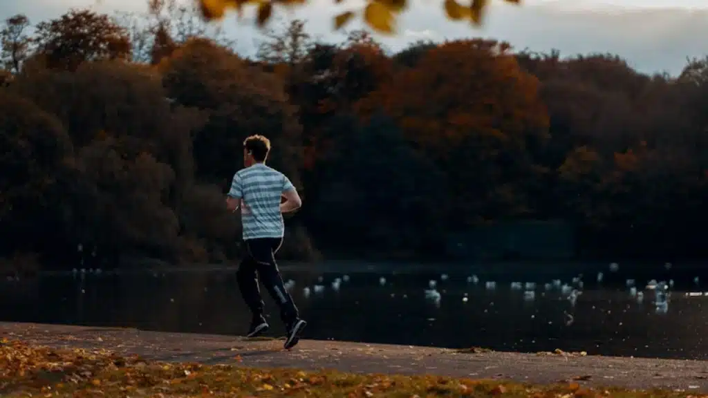 Husband jogging in a park while partner sits on the sidelines