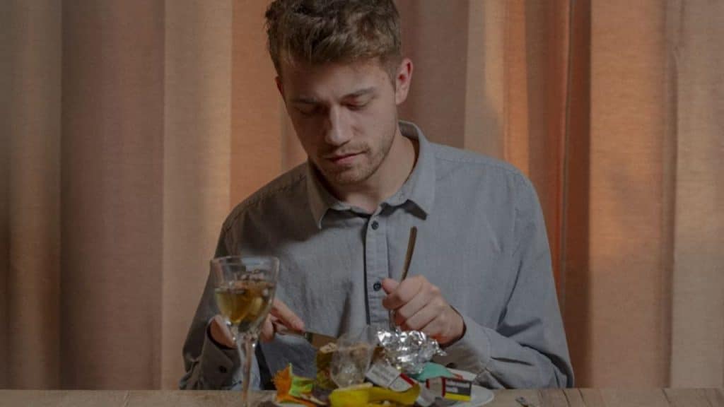 Man reluctantly eating an unhealthy meal at the dinner table