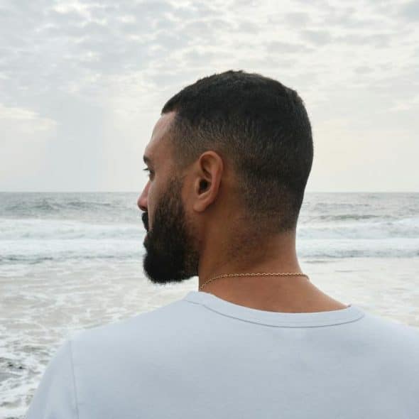 A man standing on the beach looking at the ocean.