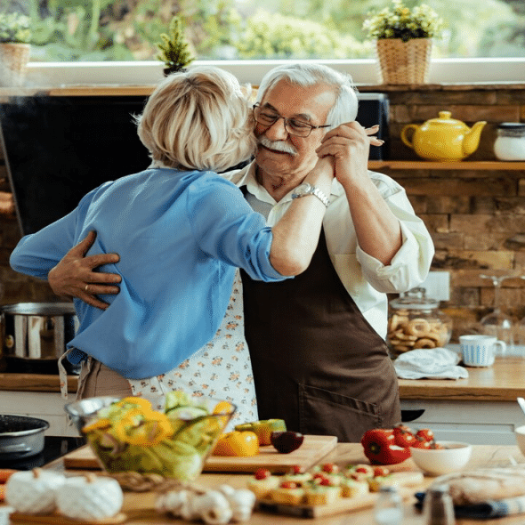 A mature couple slow dancing in the kitchen