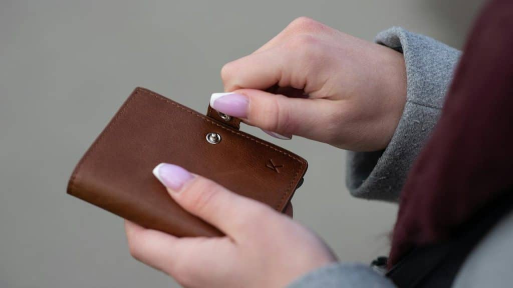 A person opens a small brown wallet.