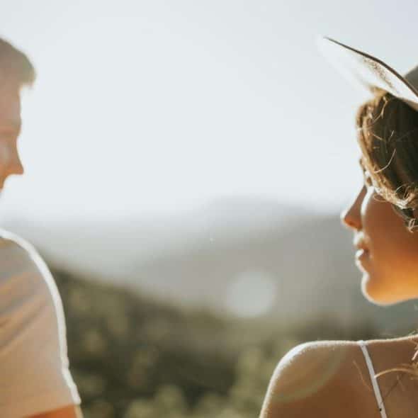 A man and woman outdoors with the sun setting in the background.