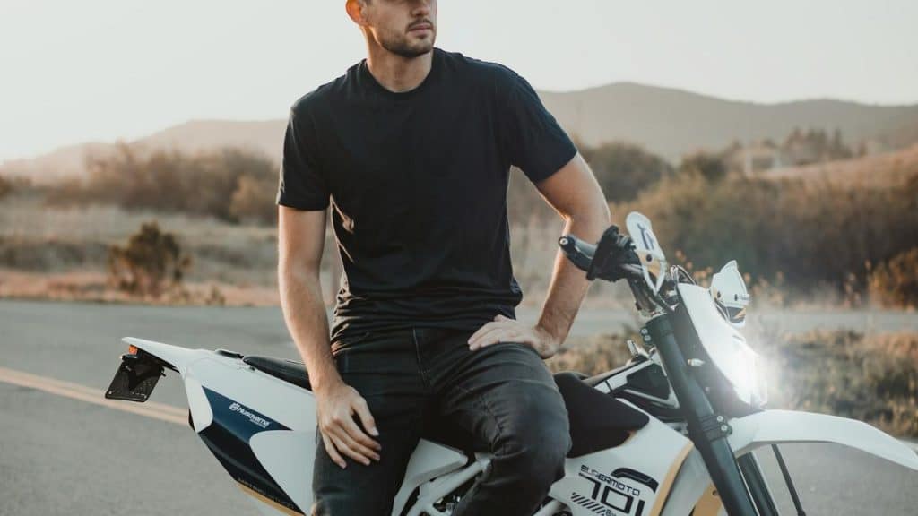 A man sitting on a motorcycle on a road at sunset.