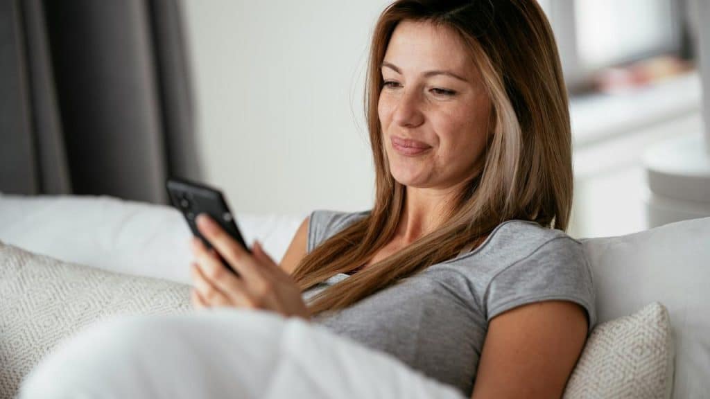 A woman lying on a couch looking at her phone.