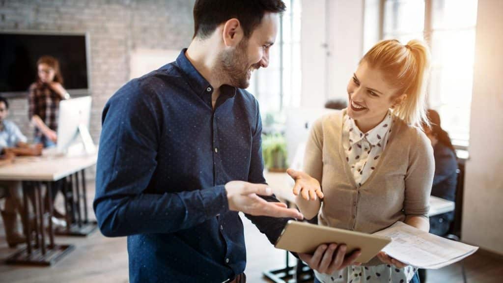 A man and woman smiling and talking in an office.