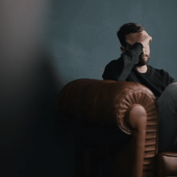 A thoughtful man sitting on a couch reflecting on his relationship