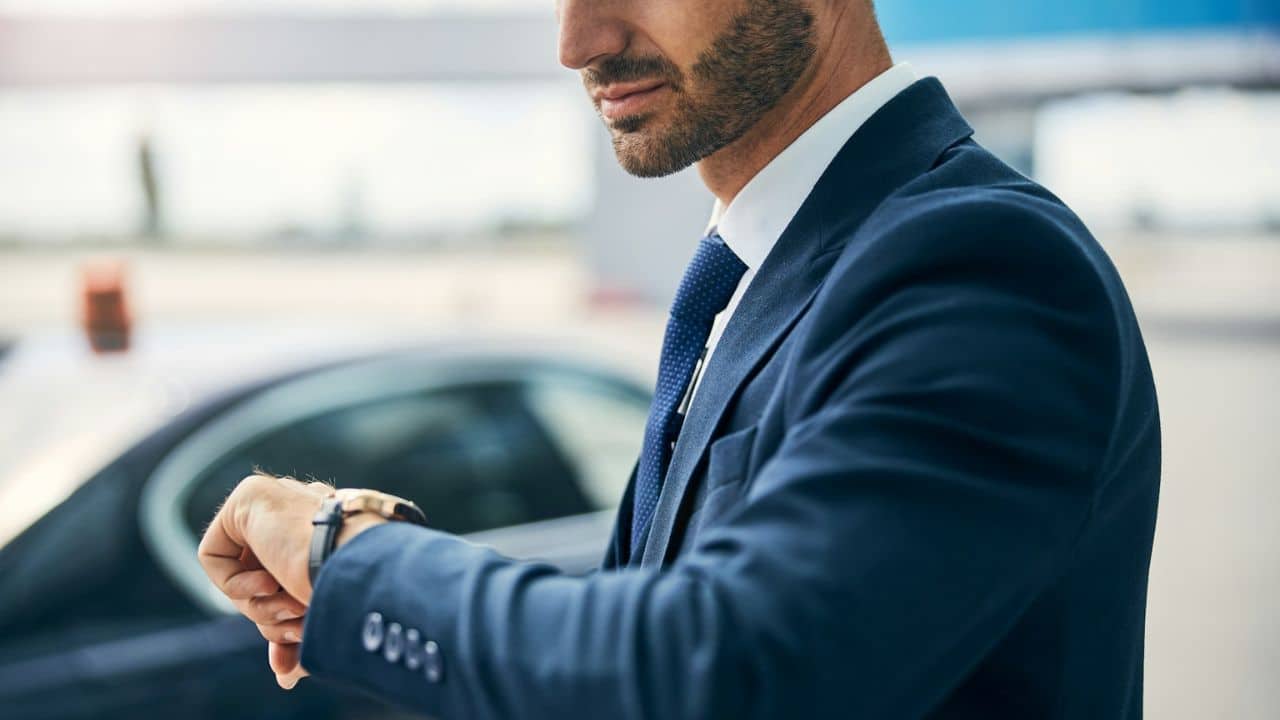 A man in a suit checks the time on his watch.