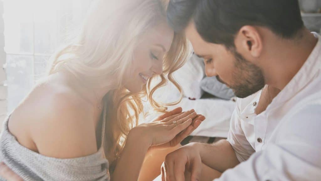 A couple smiling as the woman admires a ring on her finger.
