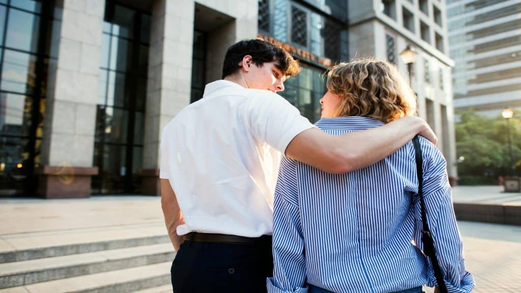 A man with his arm over his girlfriend’s shoulder