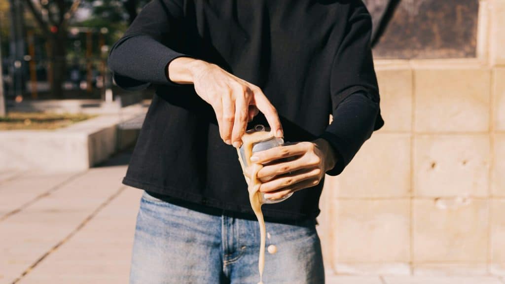 A man holding an overflowing can of soda