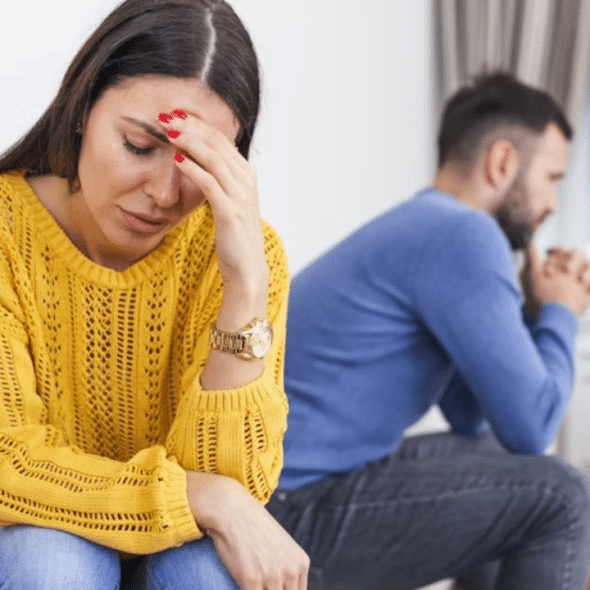 Couple sitting on a couch in silence, both looking away from each other