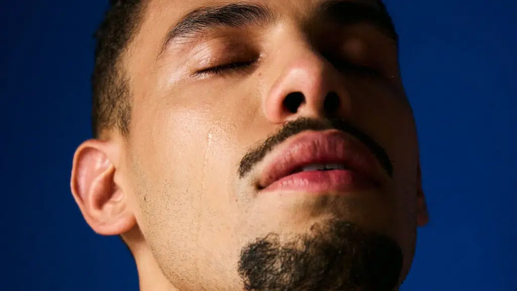 A person with their eyes closed has a tear rolling down their cheek.