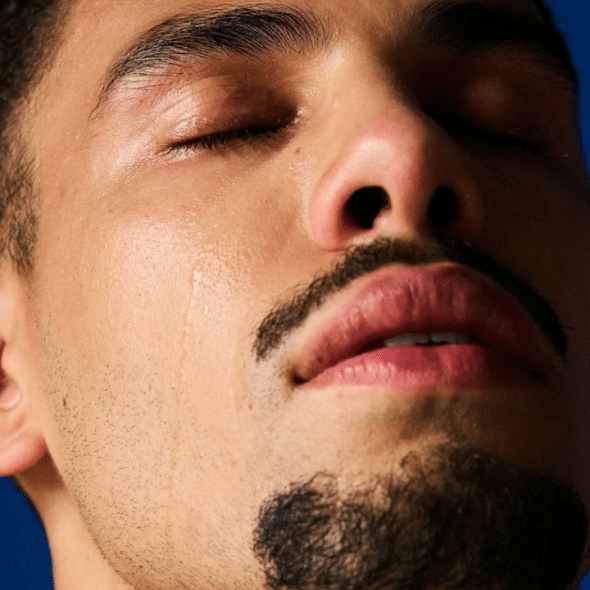 A person with their eyes closed has a tear rolling down their cheek.