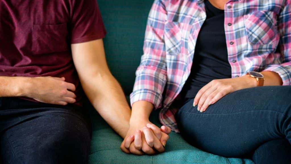 A couple holding hands on the couch