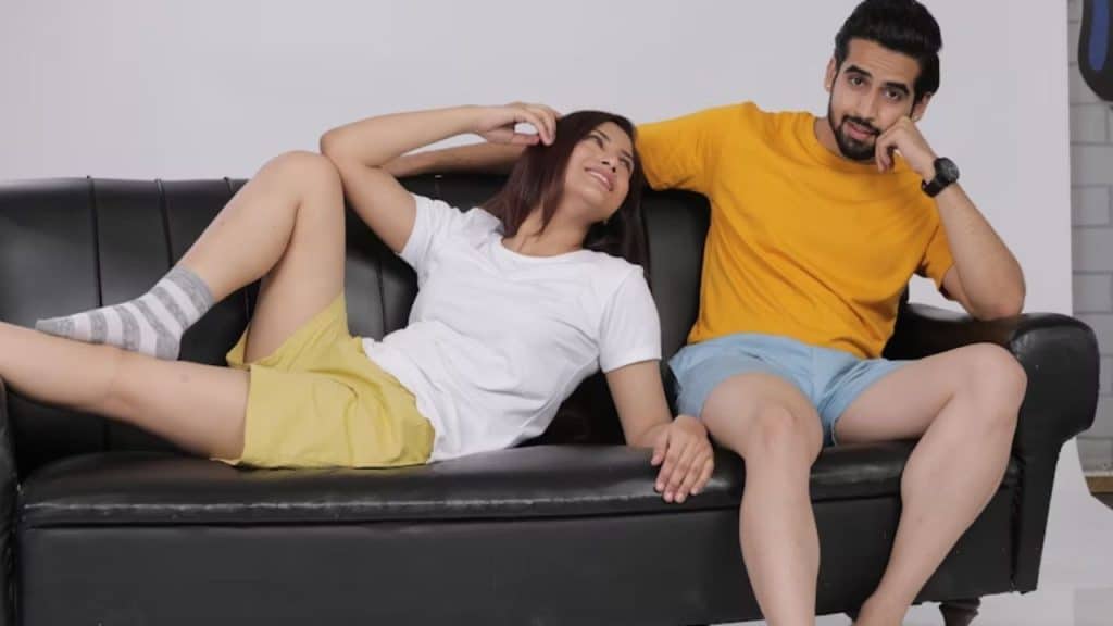 A man sitting on a couch deep in thought while his wife talks beside him