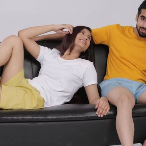 A man sitting on a couch deep in thought while his wife talks beside him