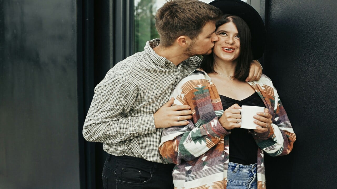 A man kissing his wife on the cheek.