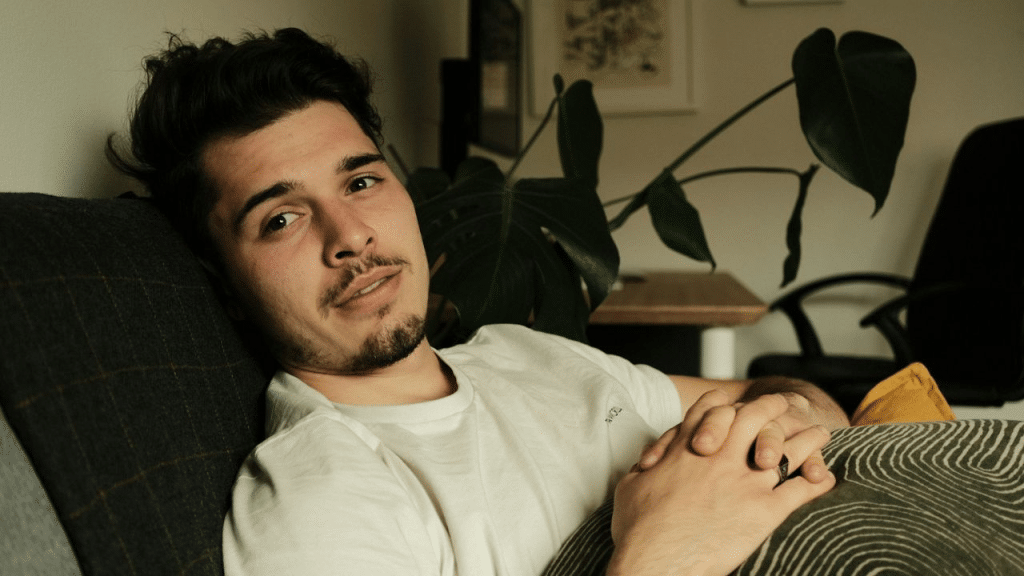 A handsome man with a mustache and beard reclines on a couch.