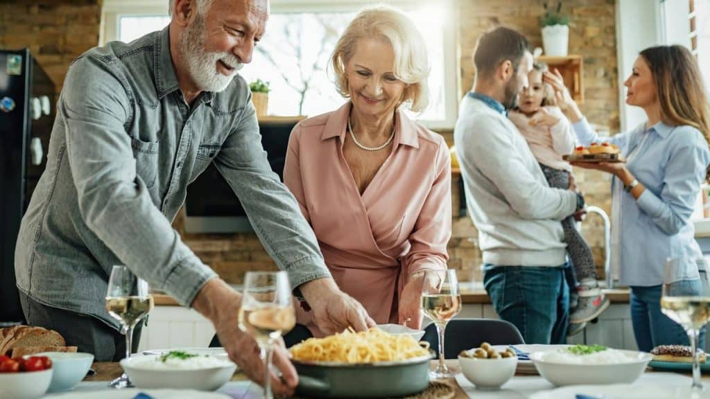A family gathering in the kitchen preparing and sharing a meal.