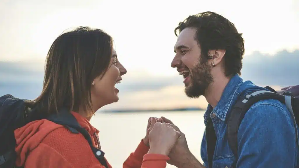 A couple laughing and holding hands outdoors.