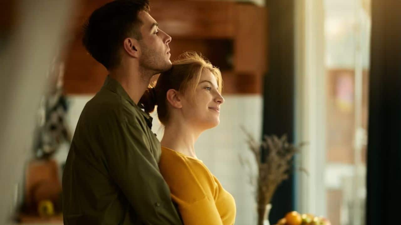 A husband hugging his wife in the kitchen after meal.