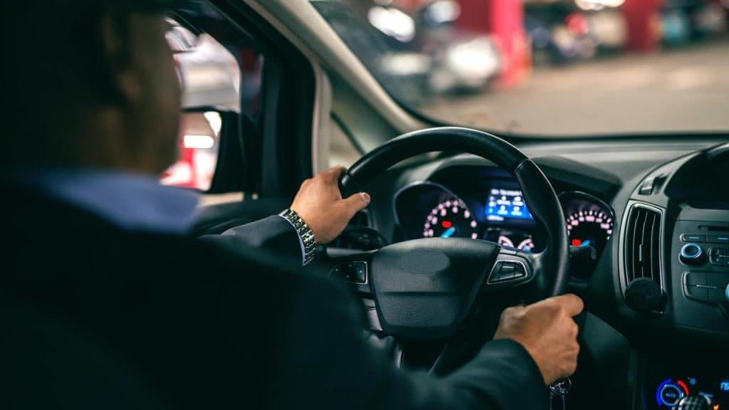 A man driving a car in an indoor parking area.