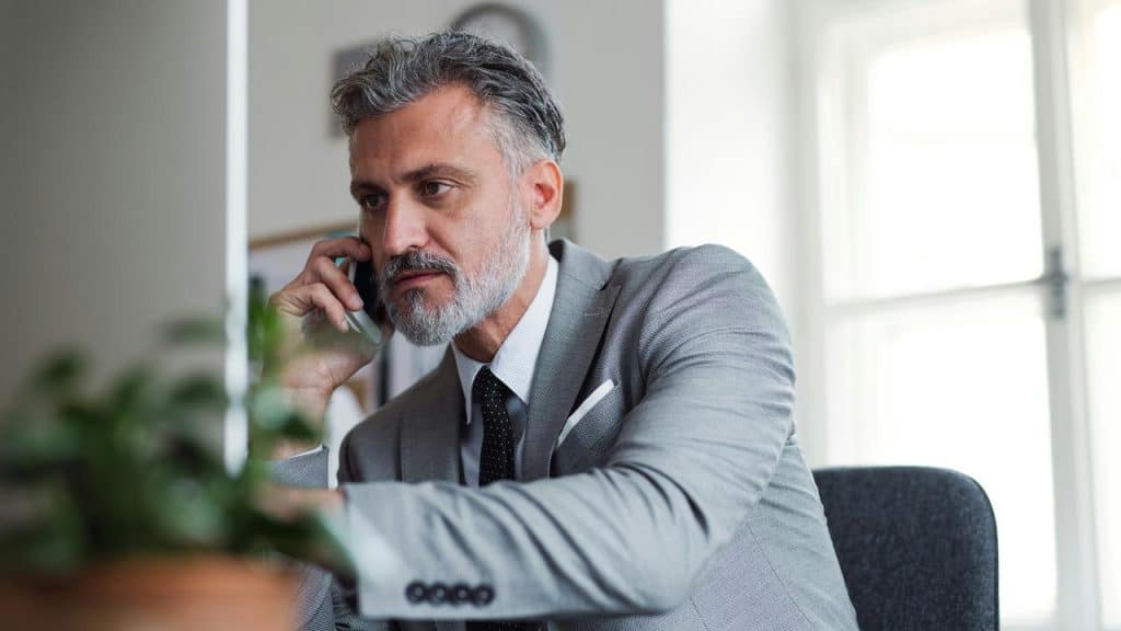 A man adjusting his tie while looking out a window.