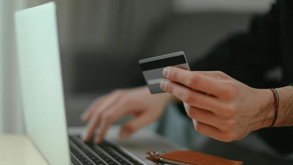 A man cooking pancakes while a woman stands nearby with a mug.